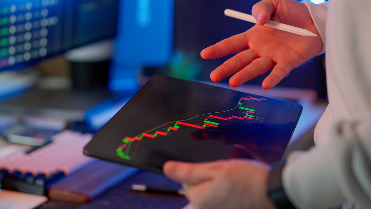 Person using a tablet to review financial and stock market data in a modern office.
